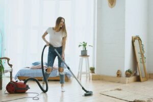 Ein flexibler Staubsaugerschlauch liegt neben einem Staubsauger auf dem Boden