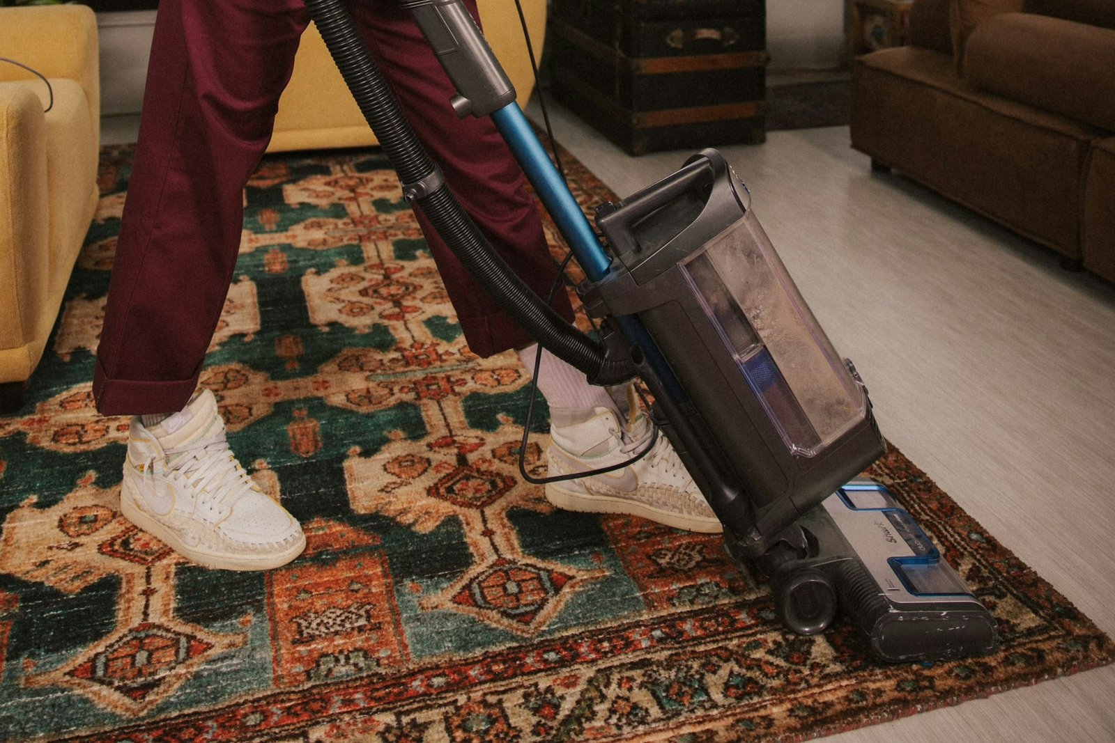 Eine Person führt eine Staubsaugerdüse über einen Boden, auf dem noch Krümel liegen